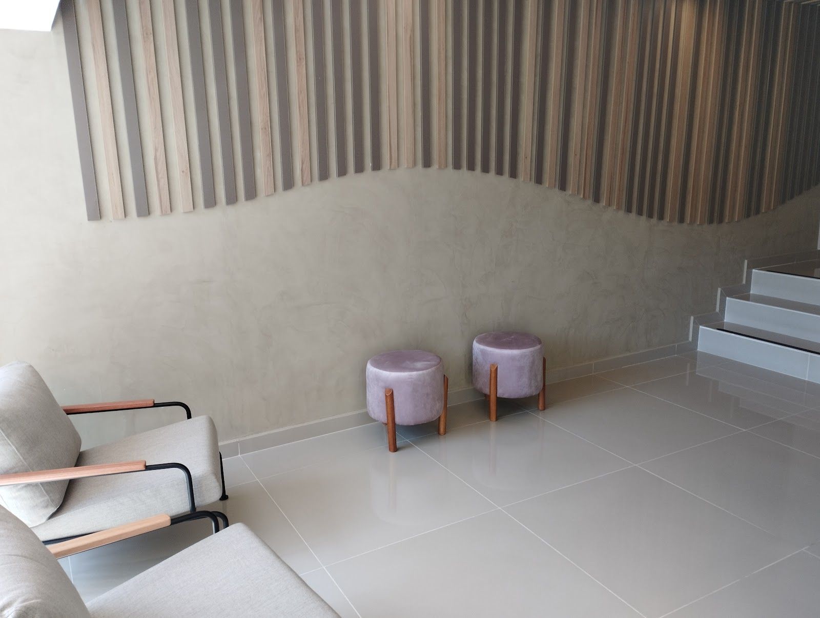 Sala de espera da LIFY, com parede de ripas de madeira em onda e banquetas rosé